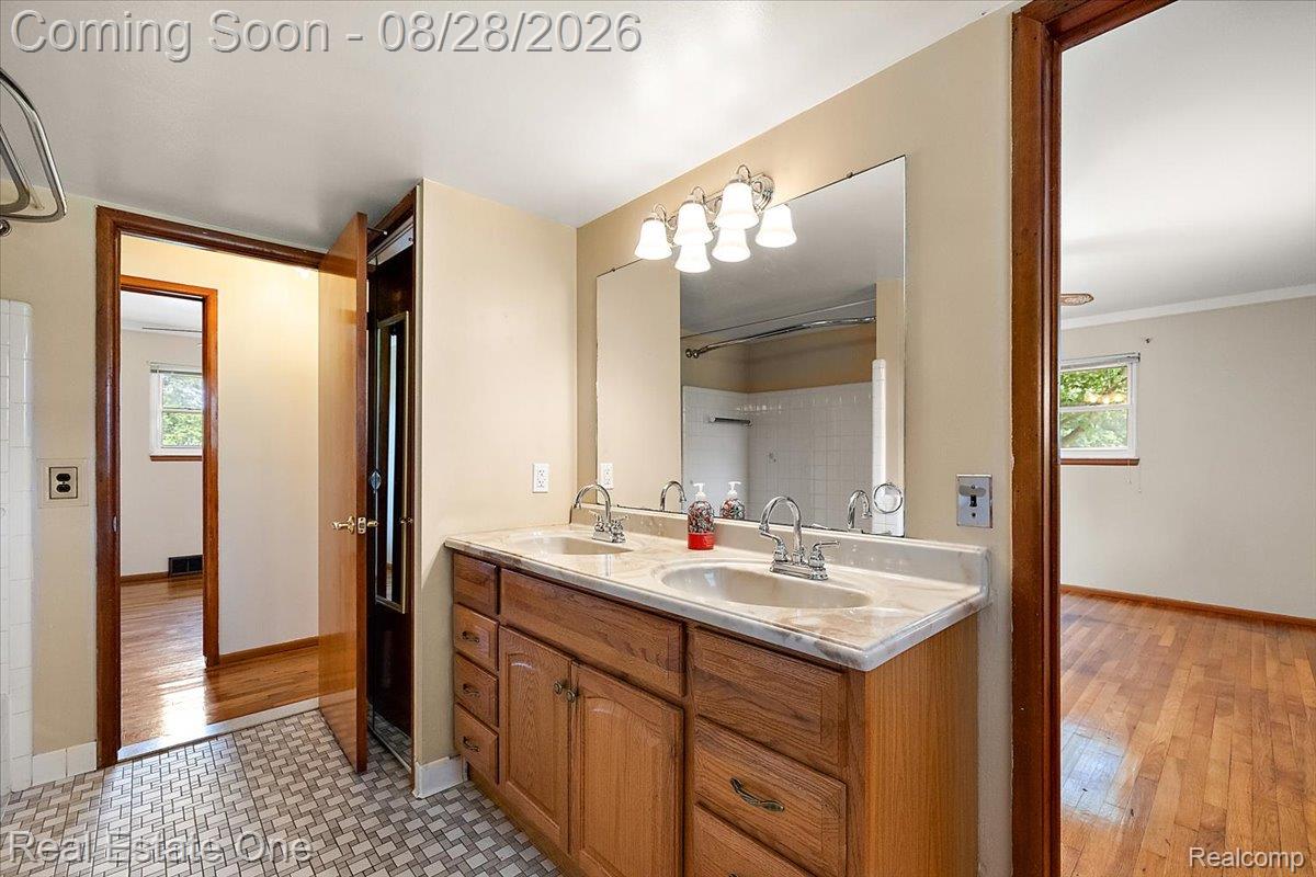 15250 34 Mile Road Armada, MI 48005 - Photo 45 of 49 Double vanity with integrated sinks, large mirrored medicine cabinet, oak-finish cabinetry, and patterned floor tile