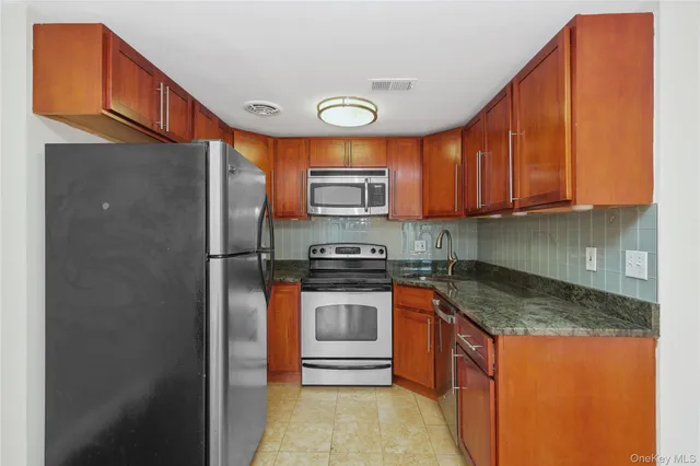 a kitchen with stainless steel appliances granite countertop a stove a sink and a refrigerator