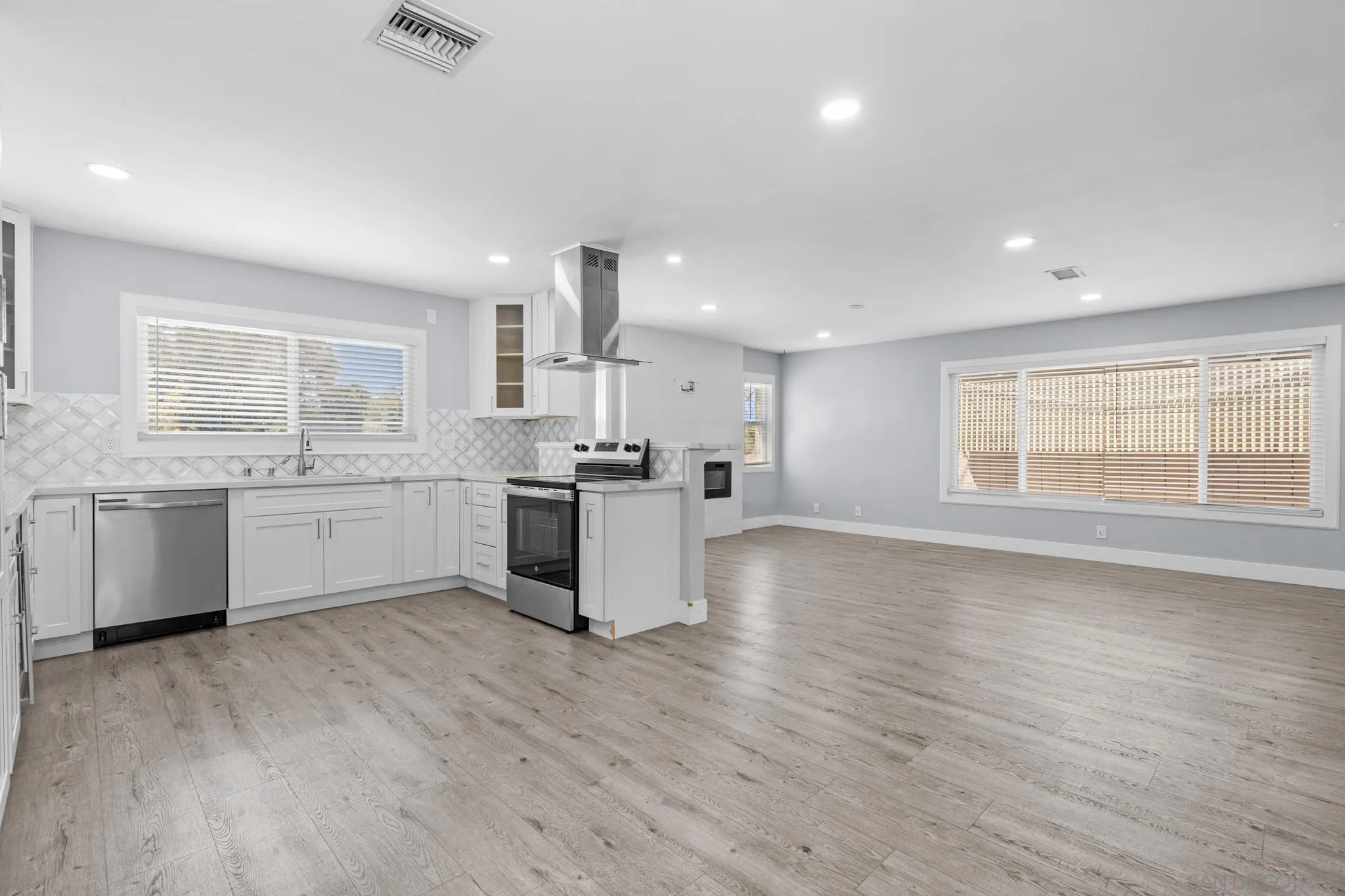 1908 Washington Street Lemon Grove, CA 91945 - Photo 5 of 54 a large white kitchen with wooden floors and white stainless steel appliances