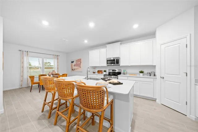 a kitchen with stainless steel appliances a table and chairs in it