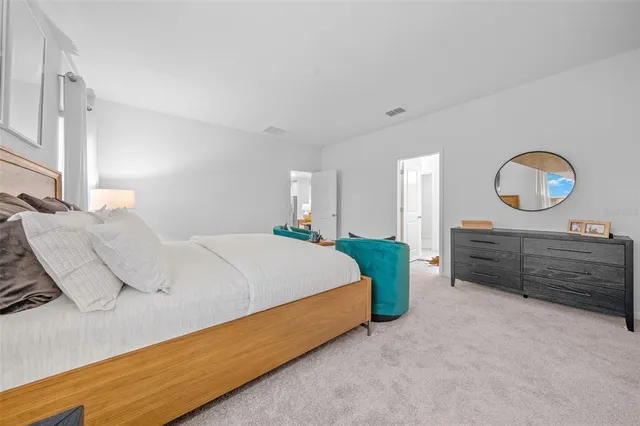 a bedroom with a bed a mirror on dresser and a table