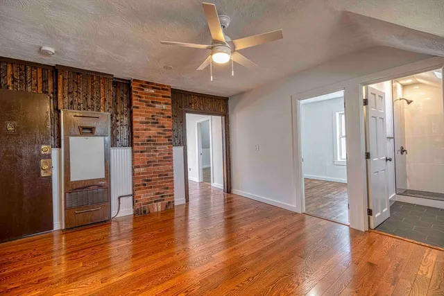 an empty room with wooden floor and a ceiling fan