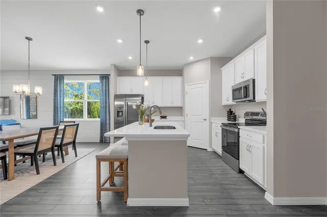 a kitchen with kitchen island a stove a sink a dining table and chairs
