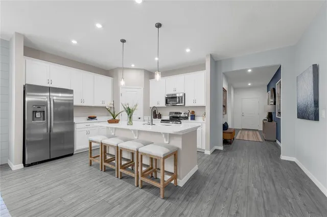 a large kitchen with a center island wooden floor stainless steel appliances and windows