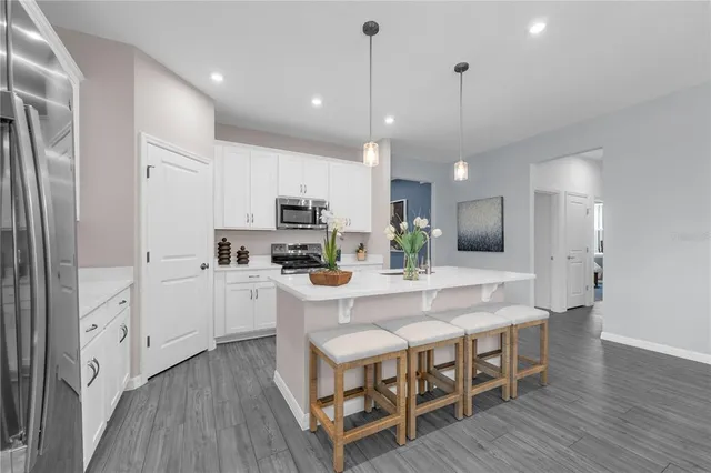 a large white kitchen with lots of counter space dining table and stainless steel appliances