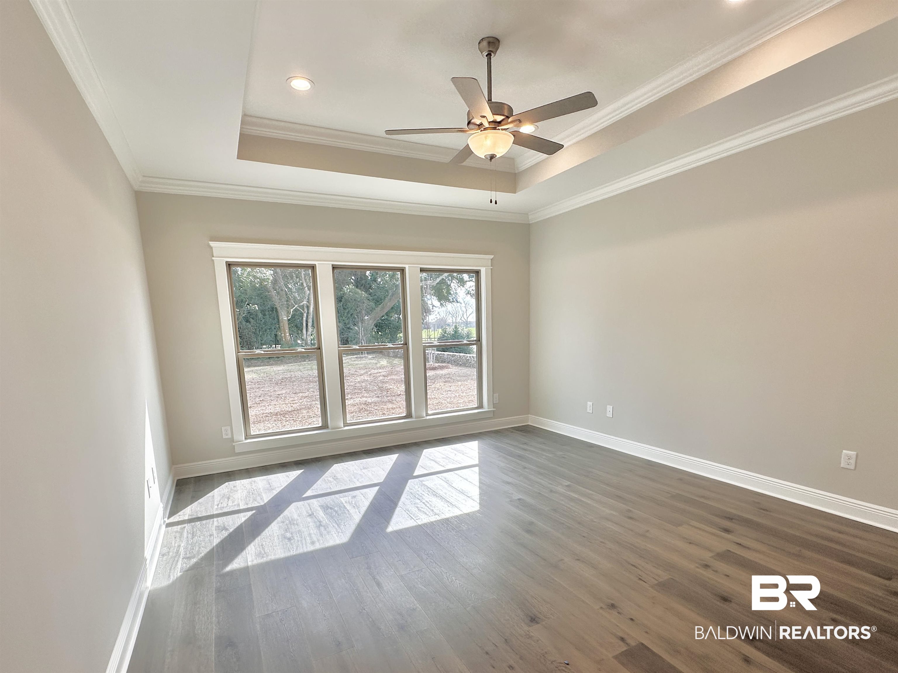 630 Kitfox Avenue Fairhope, AL 36532 - Photo 11 of 40 Spare room featuring a raised ceiling, ornamental molding, hardwood / wood-style floors, and ceiling fan