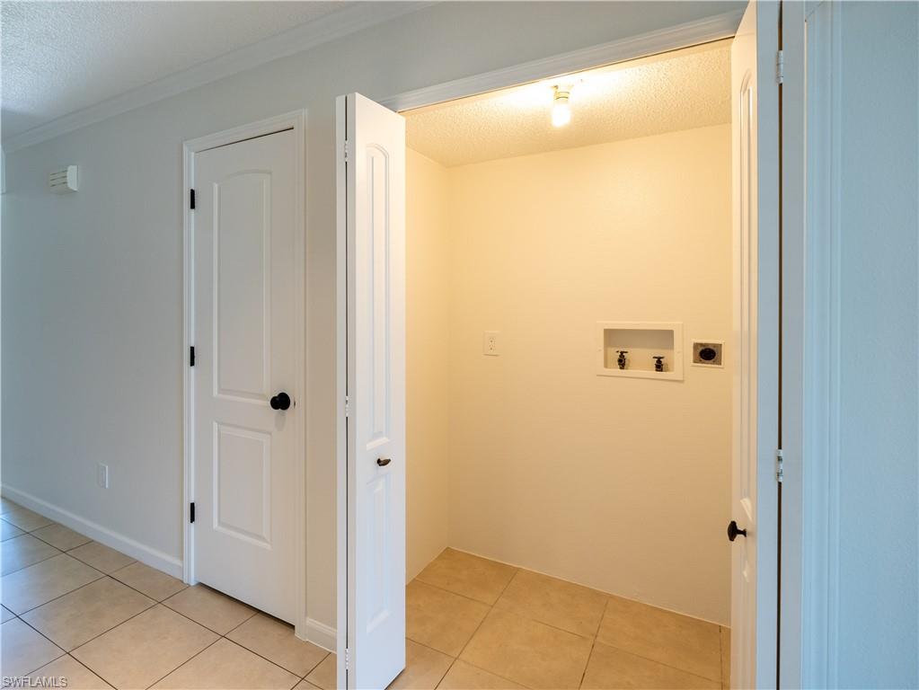 11001 Southeast Sunset Harbor Road, Unit 34 Summerfield, FL 34491 - Photo 9 of 31 Laundry room with electric dryer hookup, crown molding, light tile floors, washer hookup, and a textured ceiling