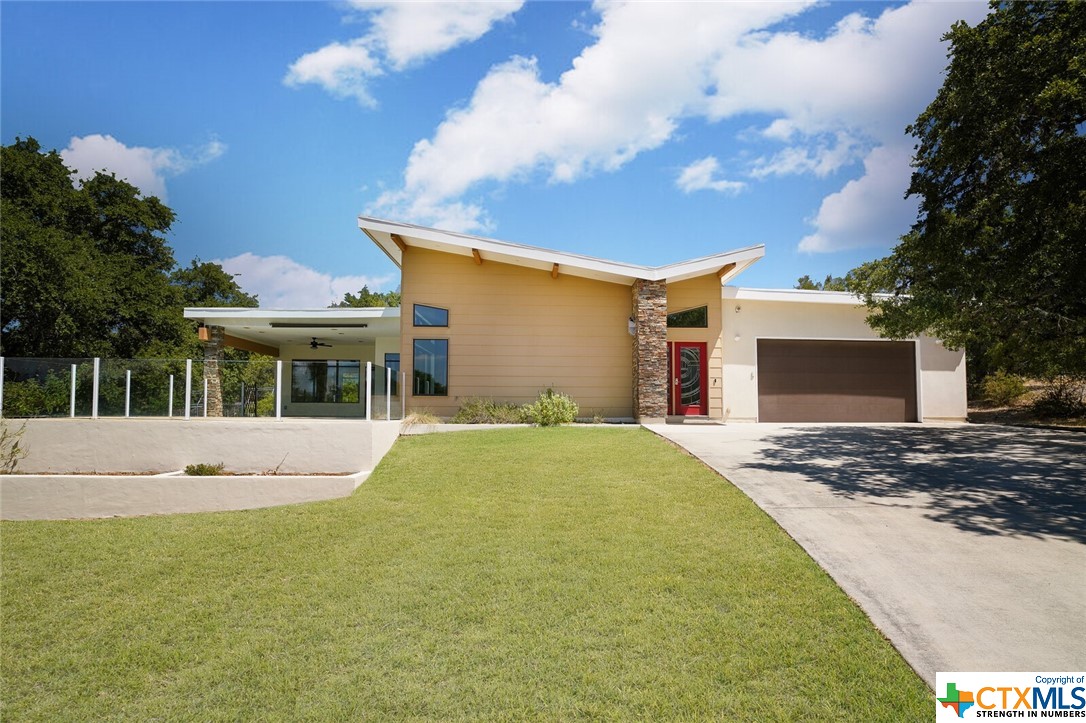 a front view of house with yard and trees in the background
