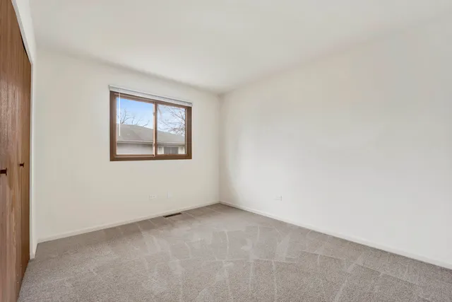 a view of an empty room with closet and a window