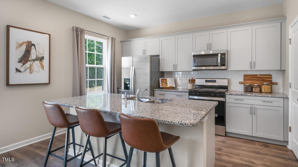 3125 White Memorial Church Road Willow Spring, NC 27592 - Photo 41 of 56 a kitchen with stainless steel appliances granite countertop a stove a sink a microwave a dining table and chairs with wooden floor