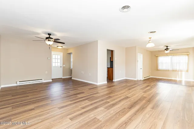 a view of an empty room with a window and wooden floor