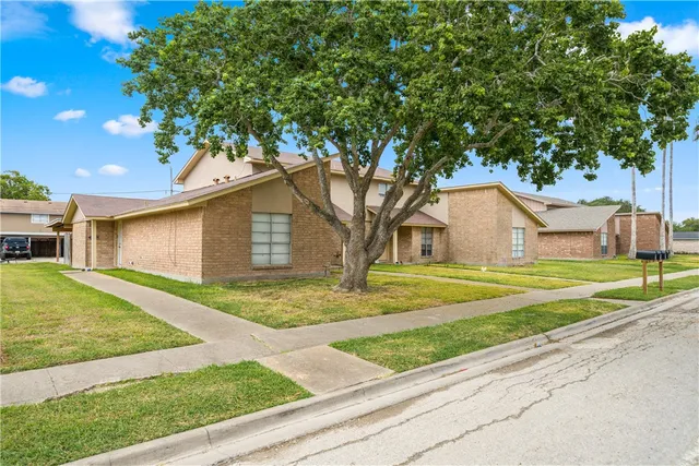 a view of a yard in front of a house with large tree