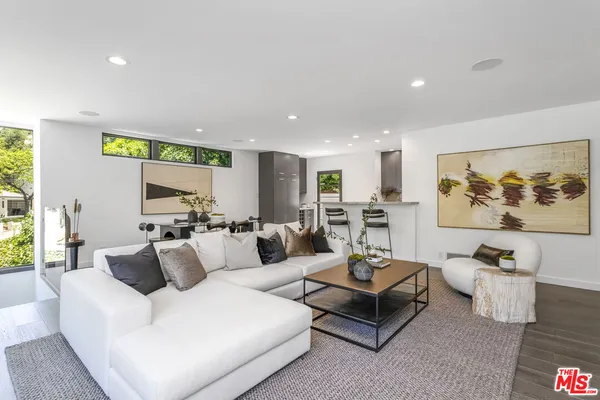 a living room with furniture kitchen view and a large window