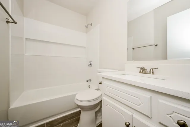 a bathroom with a granite countertop sink a toilet and bathtub