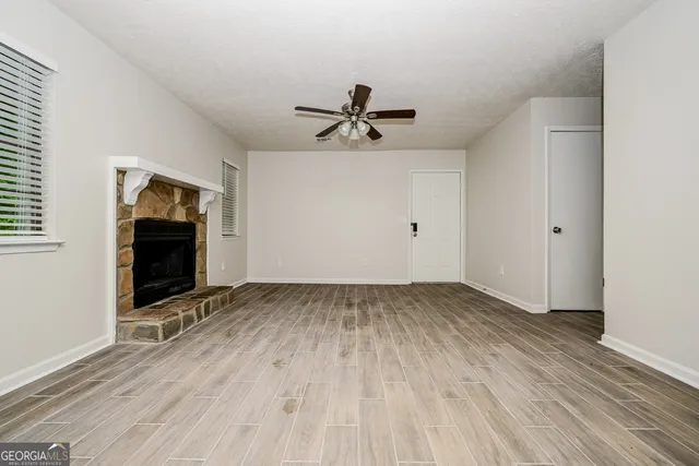 an empty room with wooden floor and ceiling fan