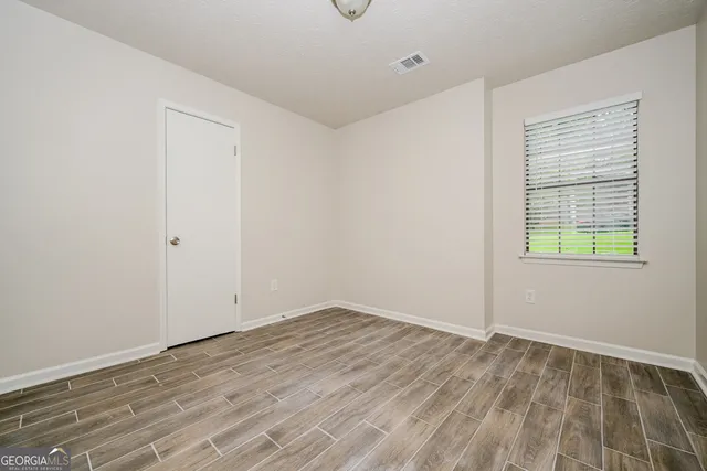 an empty room with wooden floor and windows