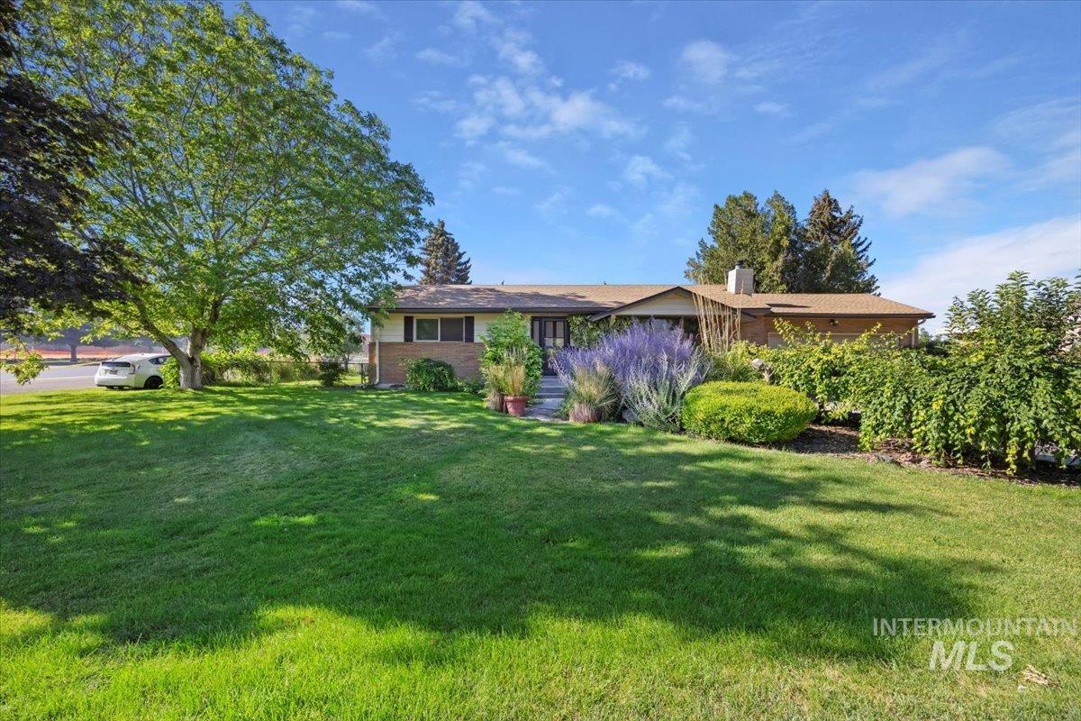 Single story home with a front lawn, a chimney, and brick siding