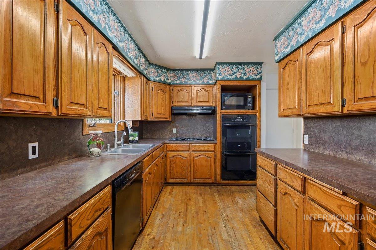 305 Lucille Street Kimberly, ID 83341 - Photo 11 of 36 Kitchen with brown cabinetry, decorative backsplash, and dark countertops