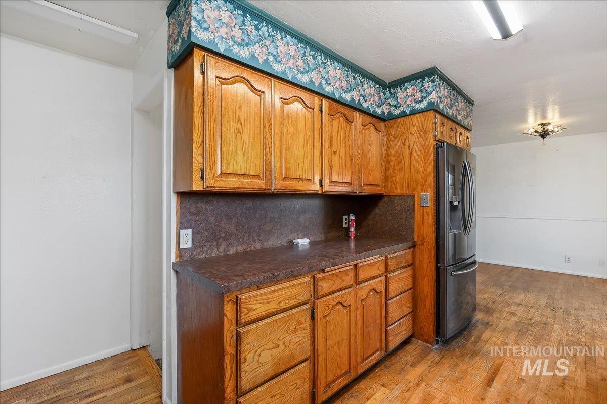 305 Lucille Street Kimberly, ID 83341 - Photo 16 of 36 Kitchen featuring tasteful backsplash, light wood finished floors, brown cabinets, and stainless steel fridge with ice dispenser