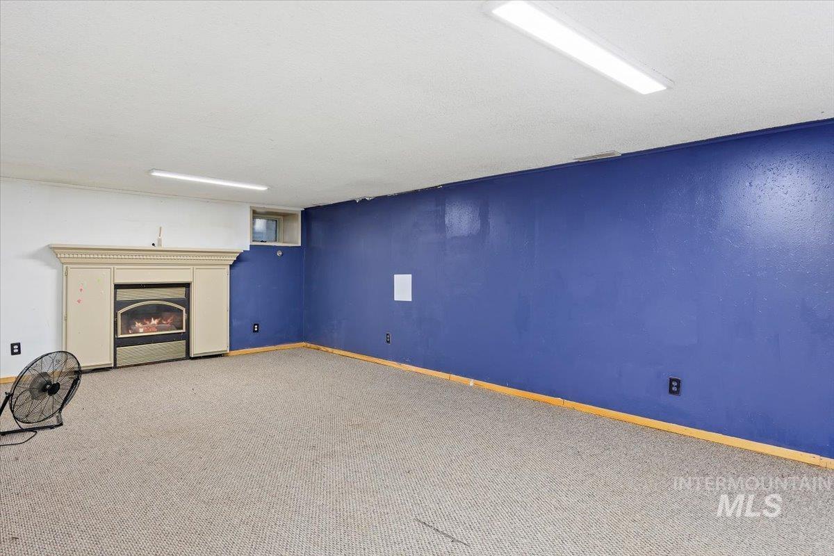 305 Lucille Street Kimberly, ID 83341 - Photo 17 of 36 Unfurnished living room featuring carpet flooring and a warm lit fireplace