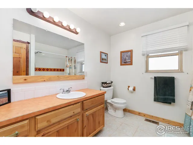 a bathroom with a granite countertop toilet sink and mirror