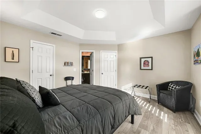 a bedroom with a bed a couch and a walk in closet with wooden floor