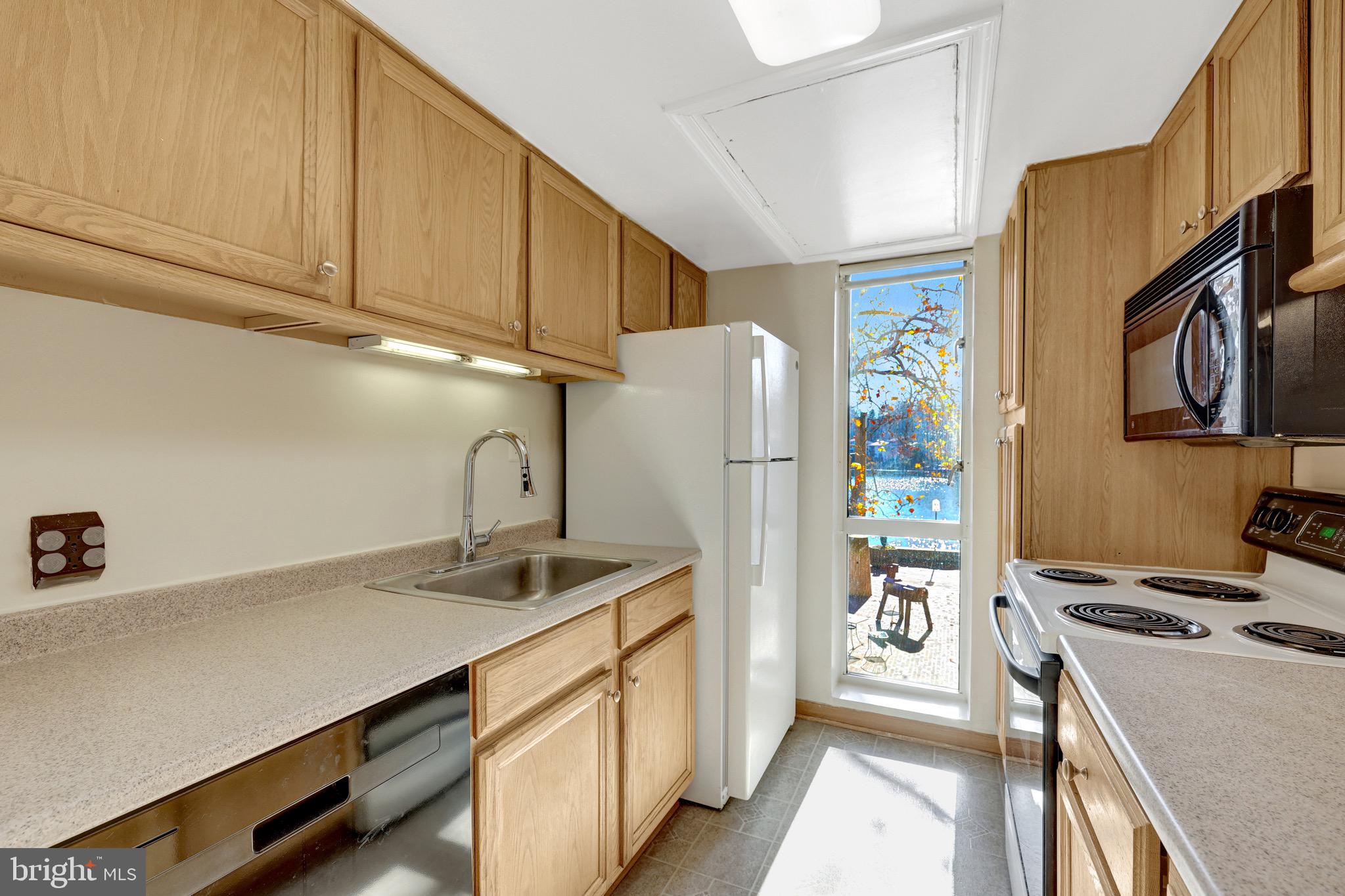 11400 Washington Plaza West, Unit 103 Reston, VA 20190 - Photo 20 of 57 a kitchen with stainless steel appliances a refrigerator a sink a stove and white cabinets