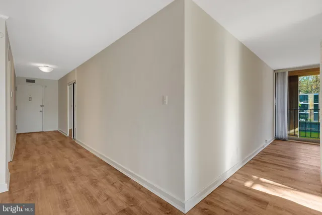 a view of an empty room with wooden floor and a window