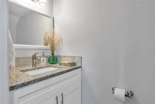 a bathroom with a granite countertop sink and a mirror