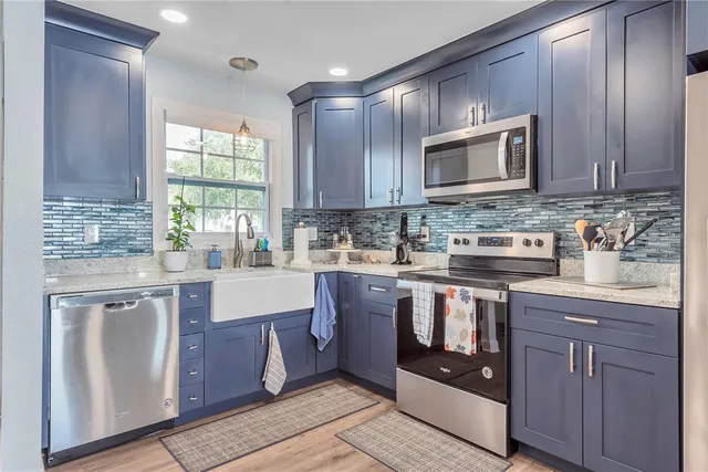 a kitchen with stainless steel appliances granite countertop a stove a sink and a microwave