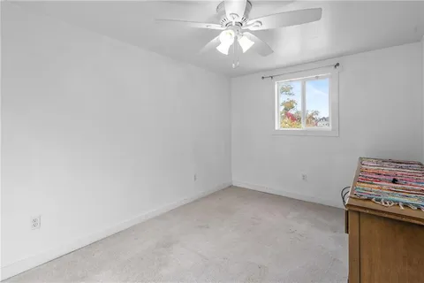 an empty room with a ceiling fan and a window