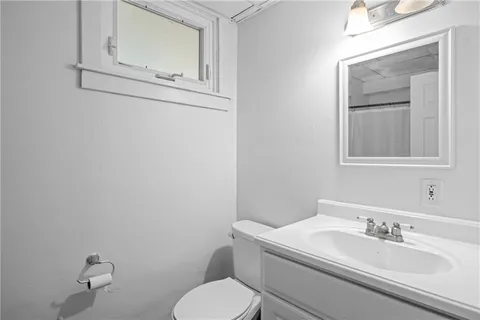 a bathroom with a toilet sink vanity and mirror