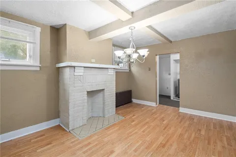 an empty room with wooden floor chandelier and windows