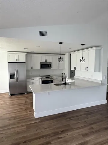 a large white kitchen with stainless steel appliances and a refrigerator