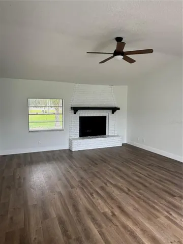 a view of empty room with wooden floor and fireplace