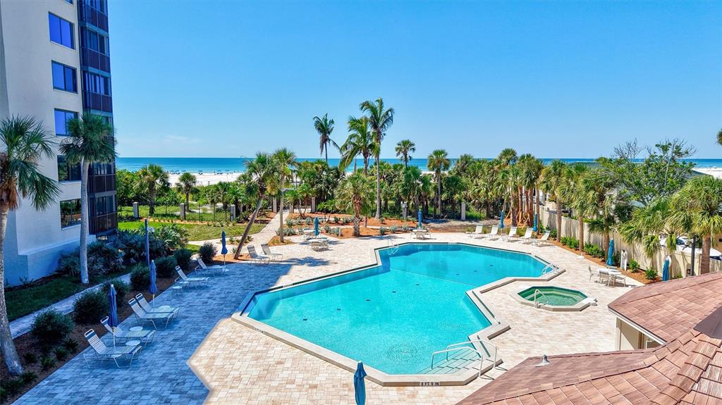 5880 Midnight Pass Road, Unit 306 Sarasota, FL 34242 - Photo 55 of 71 a view of a swimming pool with lawn chairs plants and large tree