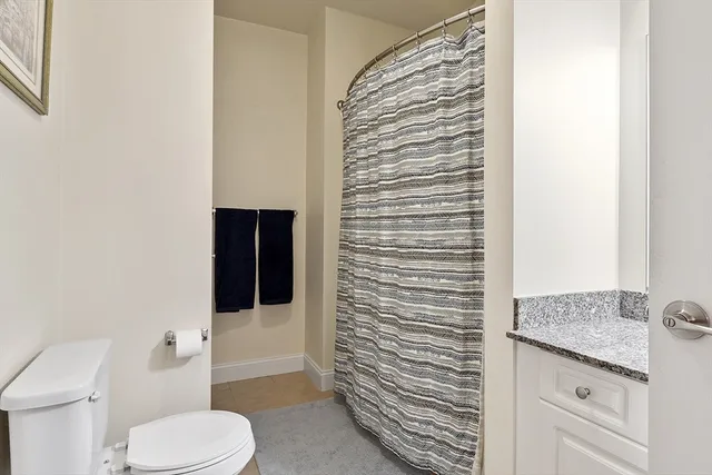 a bathroom with a granite countertop toilet and a shower
