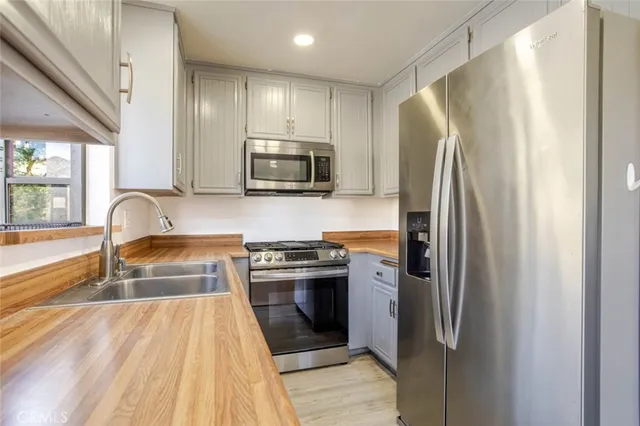 a kitchen with stainless steel appliances granite countertop a refrigerator a stove and a sink with wooden floors