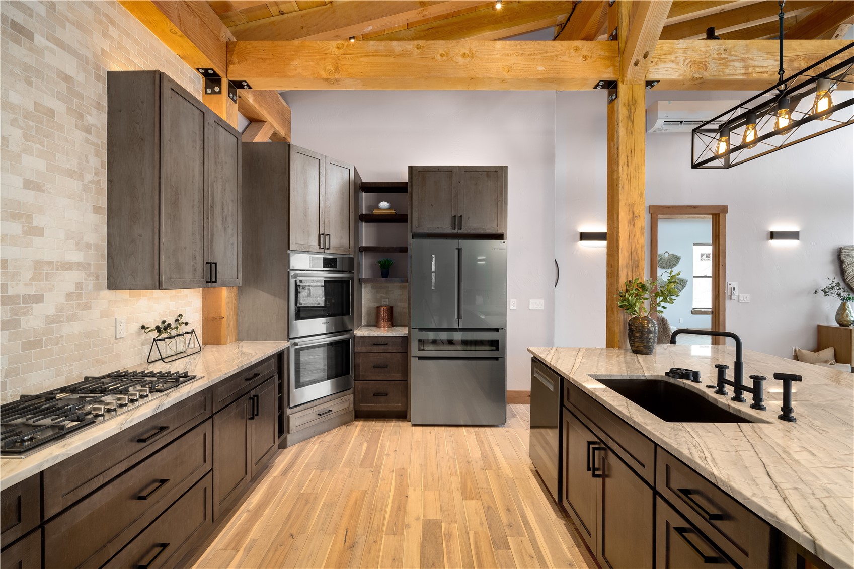 200 Sundance Court, Unit 1 Steamboat Springs, CO 80487 - Photo 13 of 50 Kitchen featuring dark brown cabinets, appliances with stainless steel finishes, decorative backsplash, light stone counters, and light wood-style floors