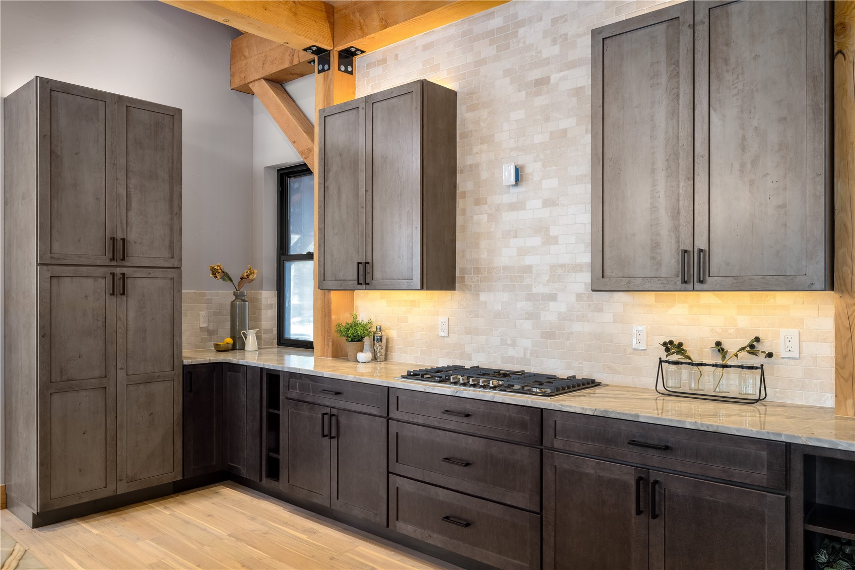 200 Sundance Court, Unit 1 Steamboat Springs, CO 80487 - Photo 15 of 50 Kitchen featuring light stone counters, light wood-type flooring, backsplash, and dark brown cabinets