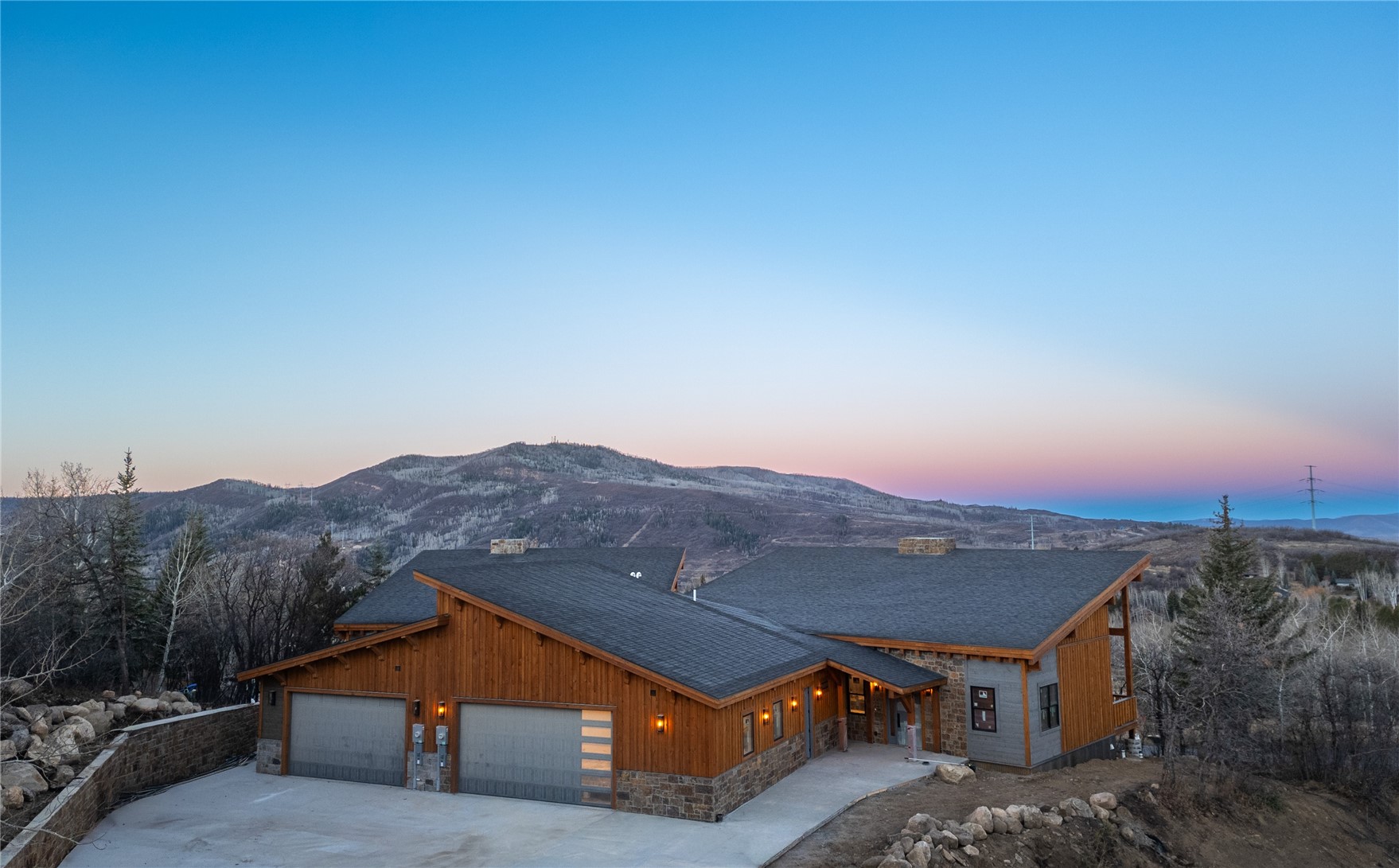 200 Sundance Court, Unit 1 Steamboat Springs, CO 80487 - Photo 45 of 50 View of front of house with stone siding, driveway, a garage, a mountain view, and a shingled roof