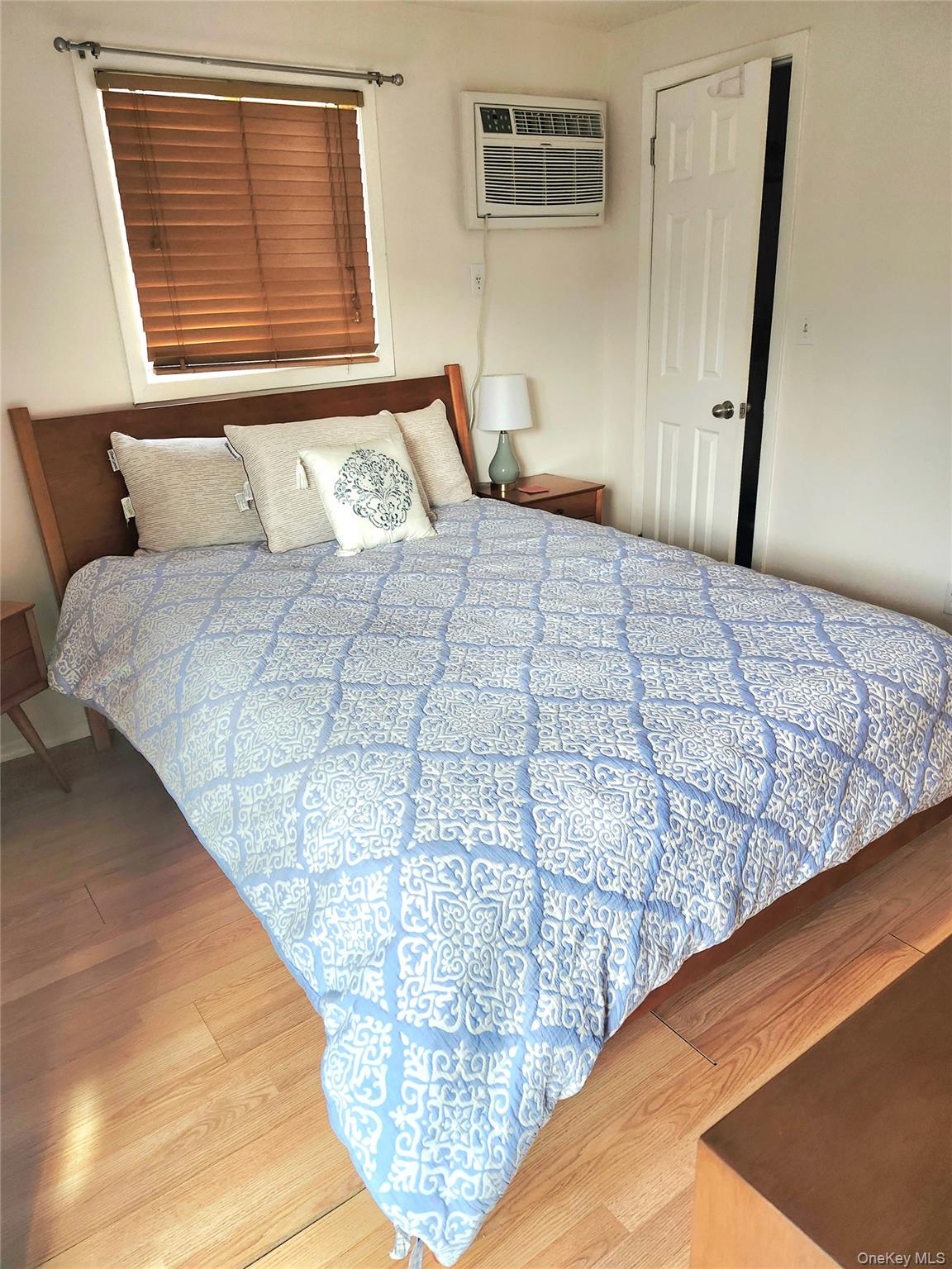 95 Springville Road South, Unit 3 Hampton Bays, NY 11946 - Photo 15 of 17 a bedroom with a bed and wooden floor