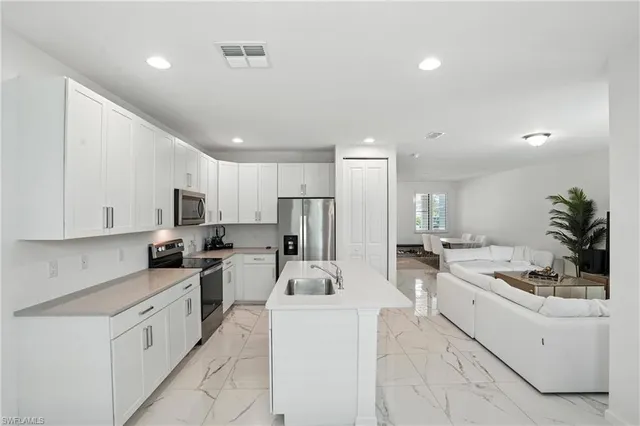 a large white kitchen with stainless steel appliances lots of counter space sink stove and cabinets