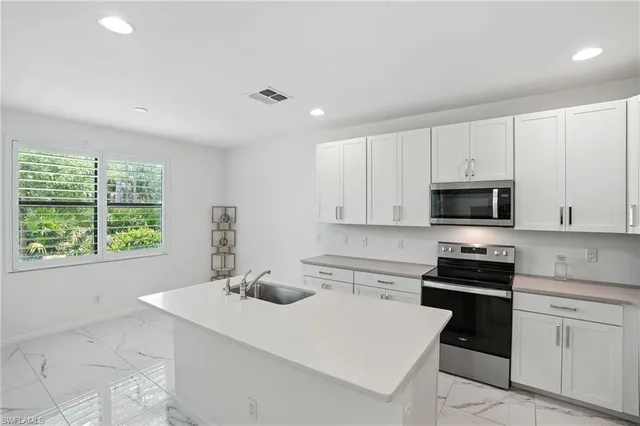 a kitchen with a sink a stove top oven and white cabinets