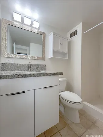 a bathroom with a granite countertop toilet sink and mirror