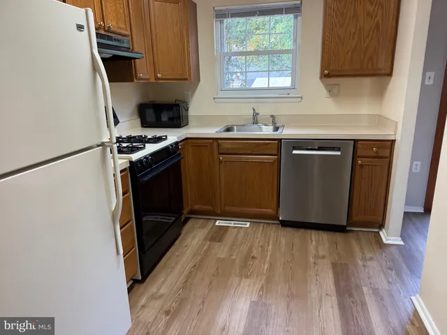 a kitchen with granite countertop a sink a stove a microwave and wooden floor