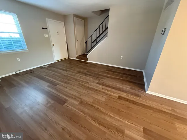 a view of an empty room with wooden floor and stairs