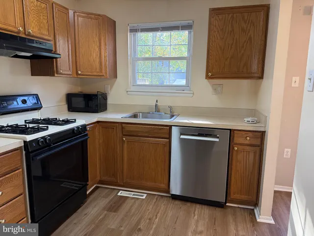a kitchen with granite countertop wooden floors and stainless steel appliances