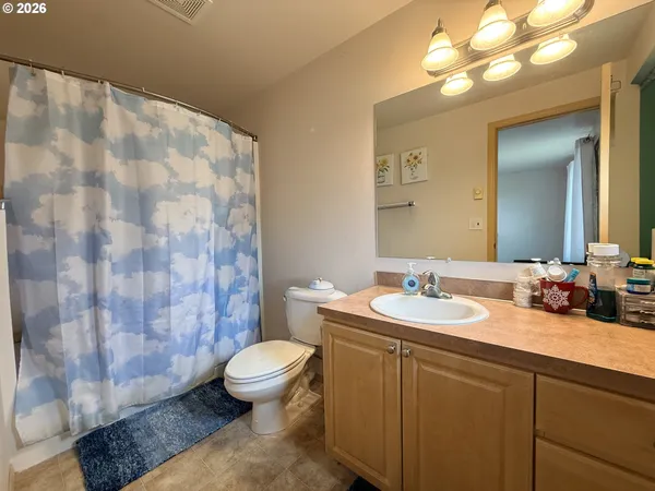 a bathroom with a sink a toilet a mirror and shower curtain