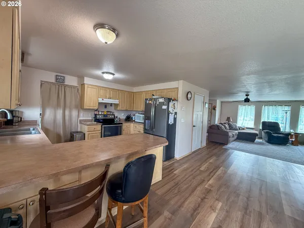 a kitchen with kitchen island a dining table chairs refrigerator and cabinets